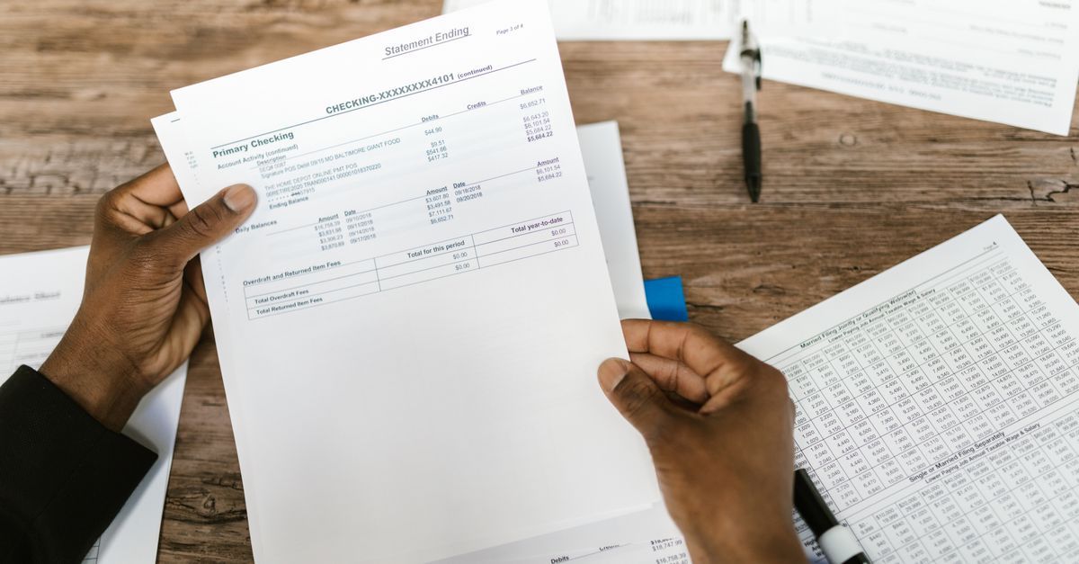Hands holding a printed bank statement over a desk