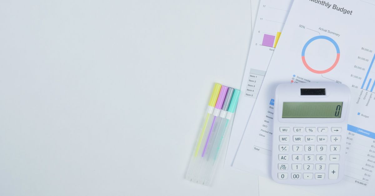 A monthly budget worksheet beside a calculator and highlighters