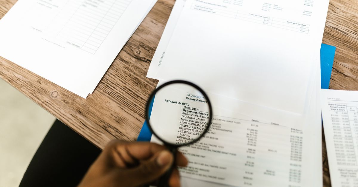 A hand holding a magnifying glass over a printed report
