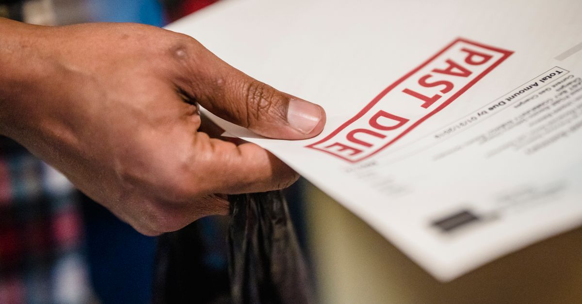 A hand holding a notice stamped PAST DUE