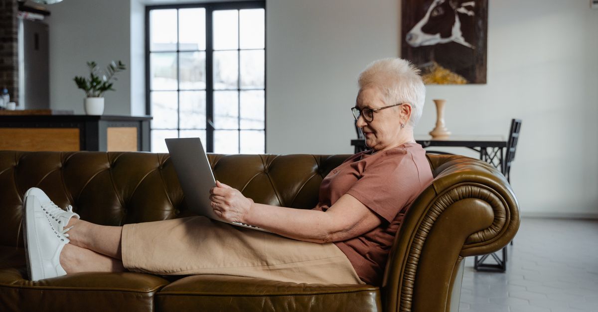 An older person using a laptop while relaxing at home