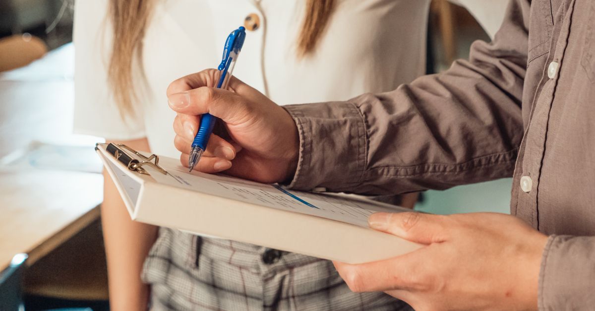 A person filling in a form on a clipboard